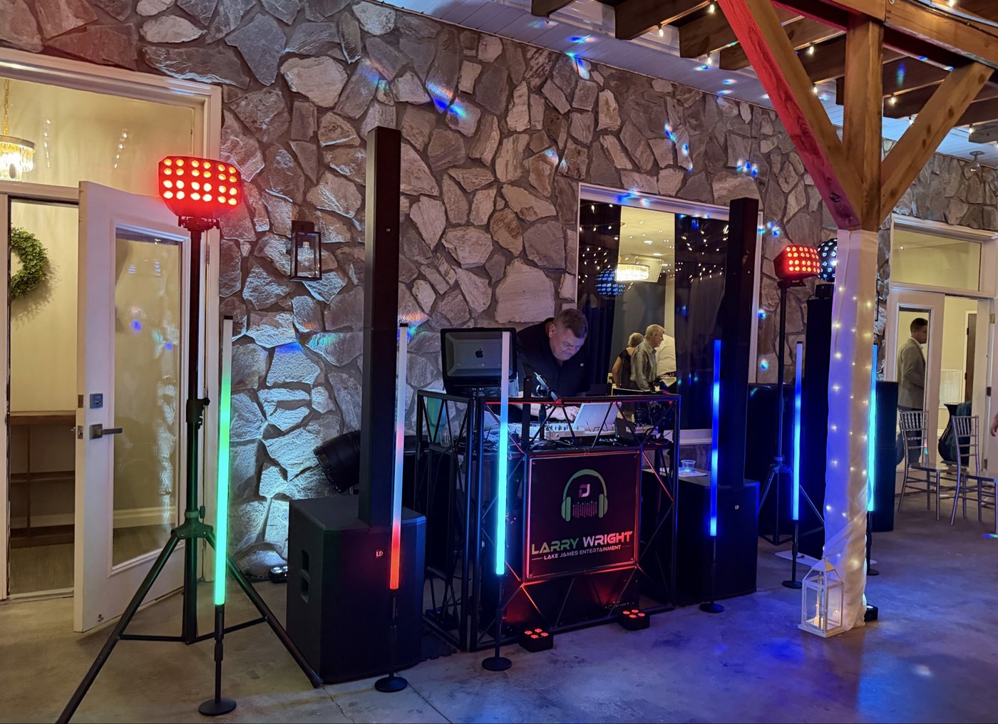 Larry Wright at his Lake James Entertainment DJ booth with colorful uplighting and light towers at an event venue