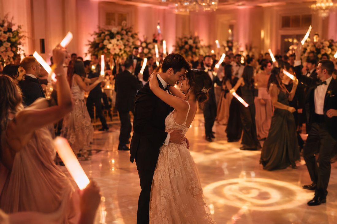 Reception hall with warm uplighting and guests waving LED light sticks